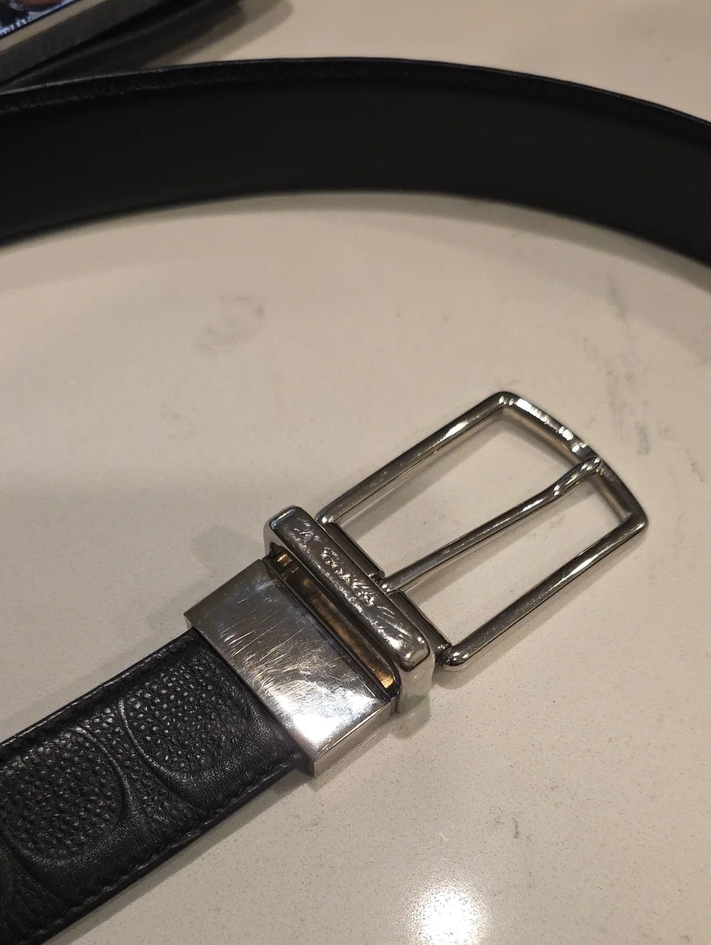 Black leather Coach belt. Reversible embossed Coach signature logo on one side.